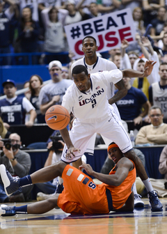 Connecticut forward DeAndre Daniels reaches for a loose ball after Syracuse small forward C.J. Fair falls between his legs.