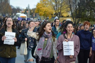 Students chant while holding papers that say 