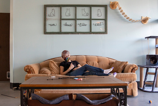 Pawsitivitea owner Alisha Reynolds pets a cat named Shelly while sitting on a couch in the cat room.