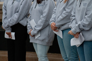 Several Remembrance Scholars stand with their hands folded waiting for the vigil to start. The Place of Remembrance was quiet while the ceremony took place and the names of the 270 victims filled the air in front of the Hall of Languages. 